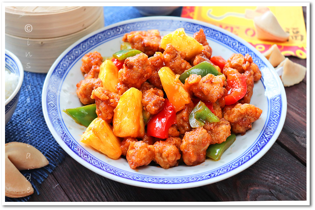 Knusprig gebackenes Schweinefleisch in Würfelform mit Ananas und Paprika in einer süß-sauren Sauce