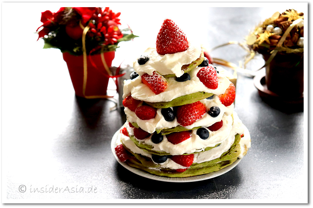 Grüne Pfannkuchen mit Sahne, Erdbeeren und Blaubeeren, drapiert als winterlicher Tannenbaum